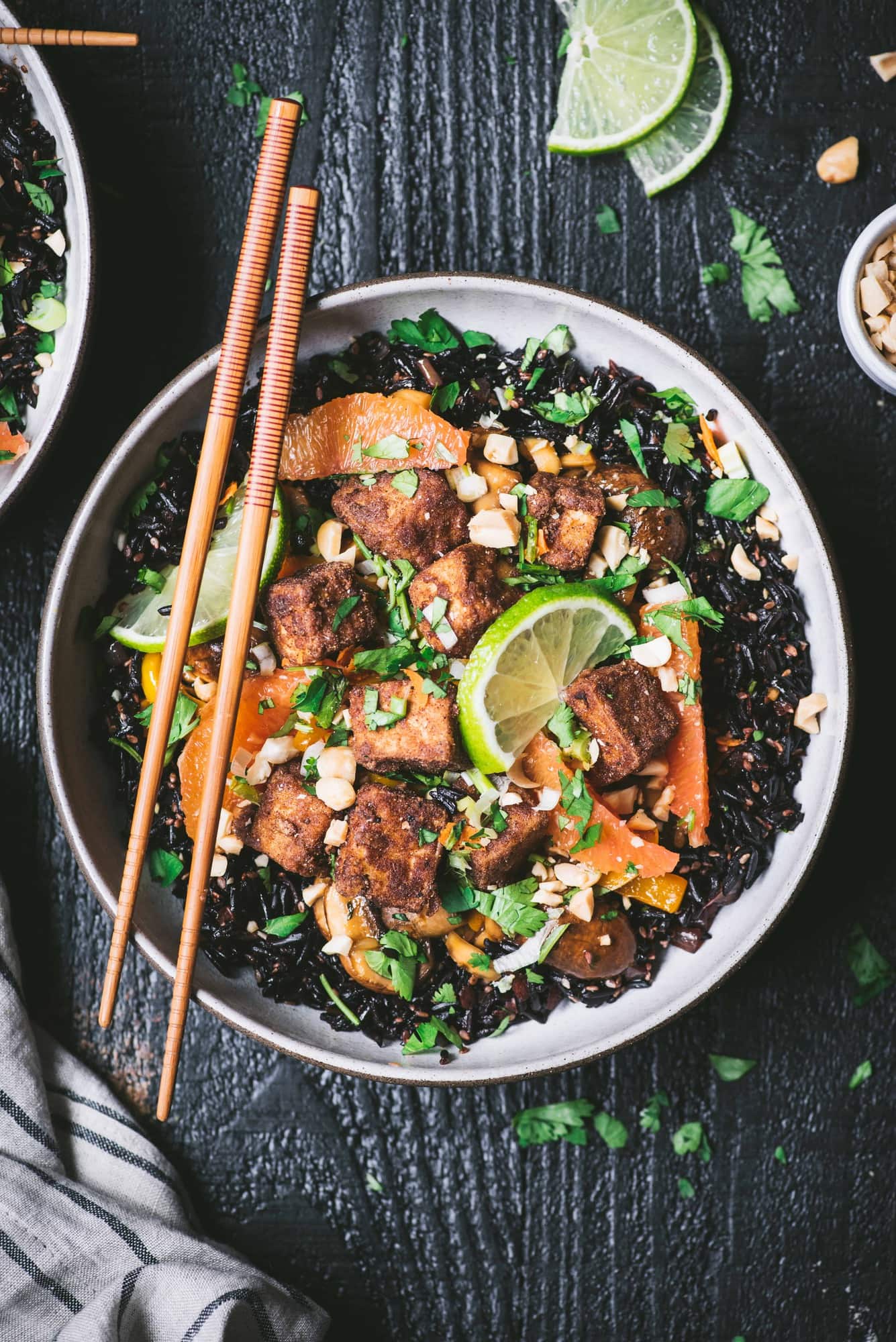 Overhead of black rice and five spice crispy tofu in a white bowl with chopsticks