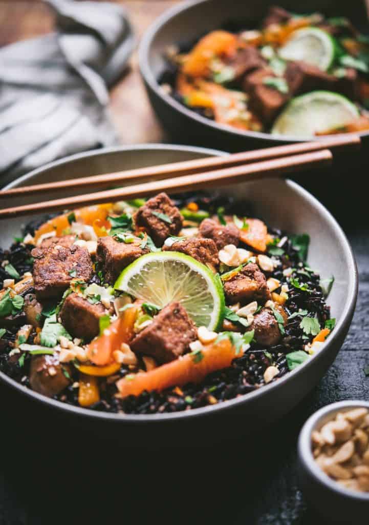 45 degree view of black rice with veggies and five spice tofu in a bowl with chopsticks