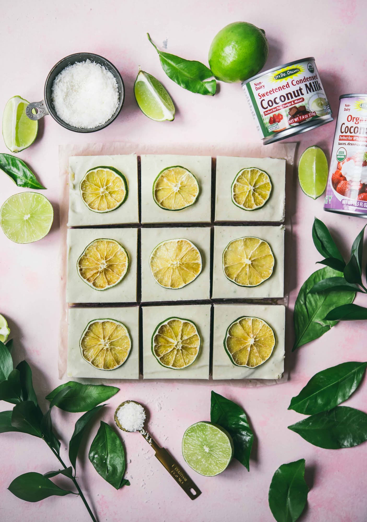 Overhead of coconut lime cheesecake bars on a pink background
