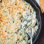 Close up of vegan spinach artichoke with spoon in pan