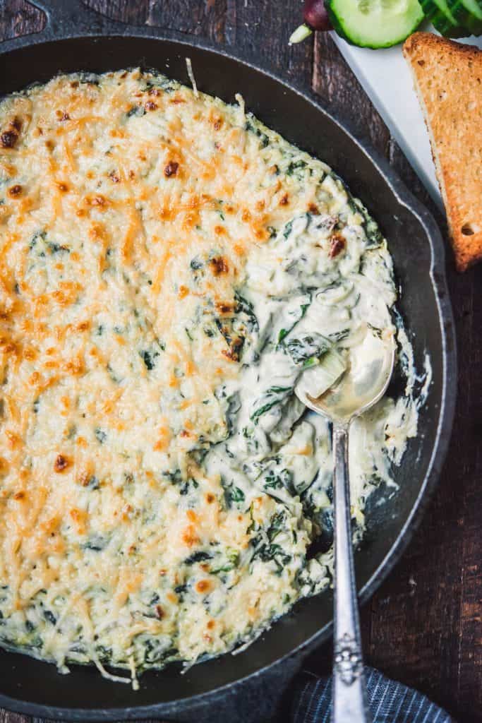 Close up of vegan spinach artichoke with spoon in pan