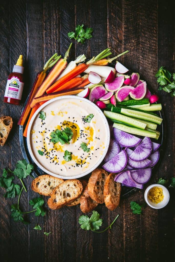Overhead of spicy sriracha white bean dip with fresh vegetables and crudites