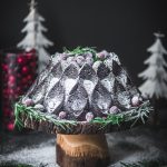 Chocolate gingerbread bundt cake on wood cake stand with dark, moody background