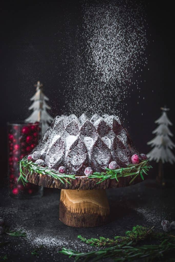 Action shot of powdered sugar falling on chocolate gingerbread bundt cake