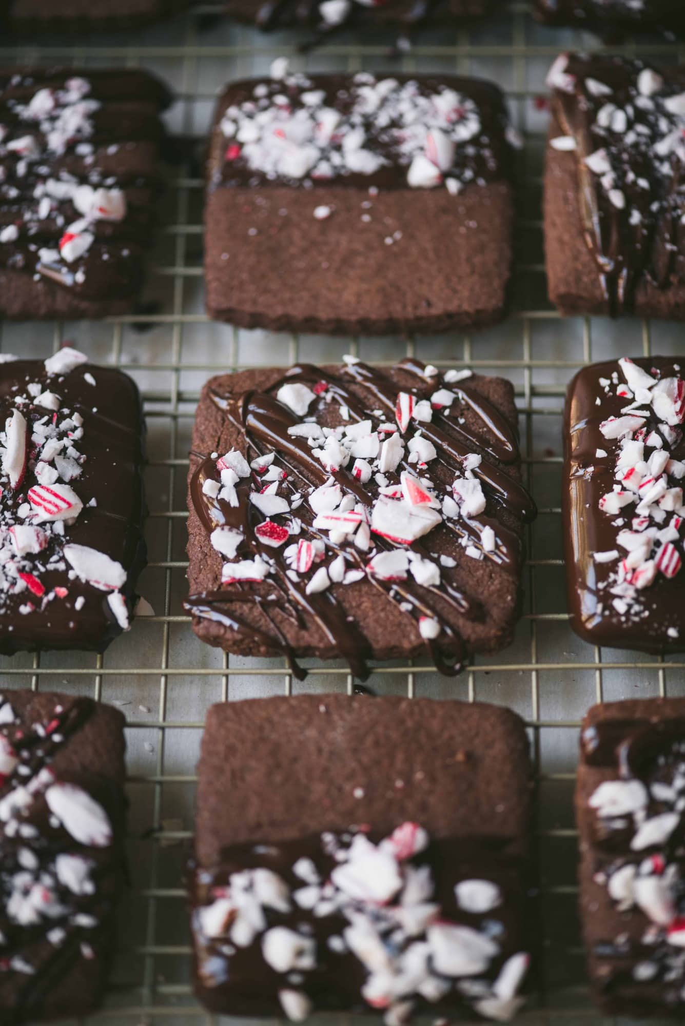 45 degree angle of chocolate dipped shortbread cookies with crushed peppermint on a cooling rack