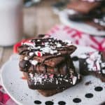 Side view of chocolate peppermint shortbread cookies on a santa plate with a glass of milk