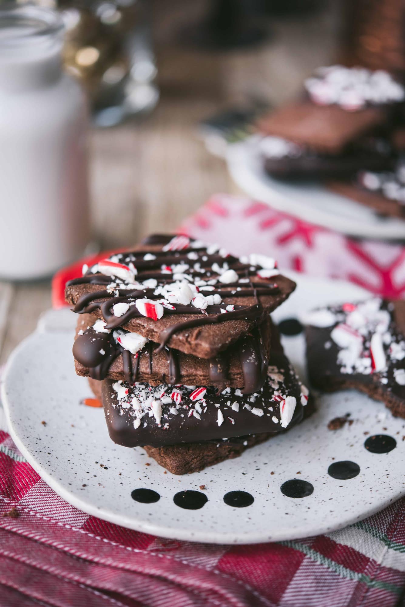 Side view of chocolate peppermint shortbread cookies on a santa plate with a glass of milk