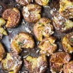 Close up overhead of crispy smashed potatoes with vegan parmesan and herbs