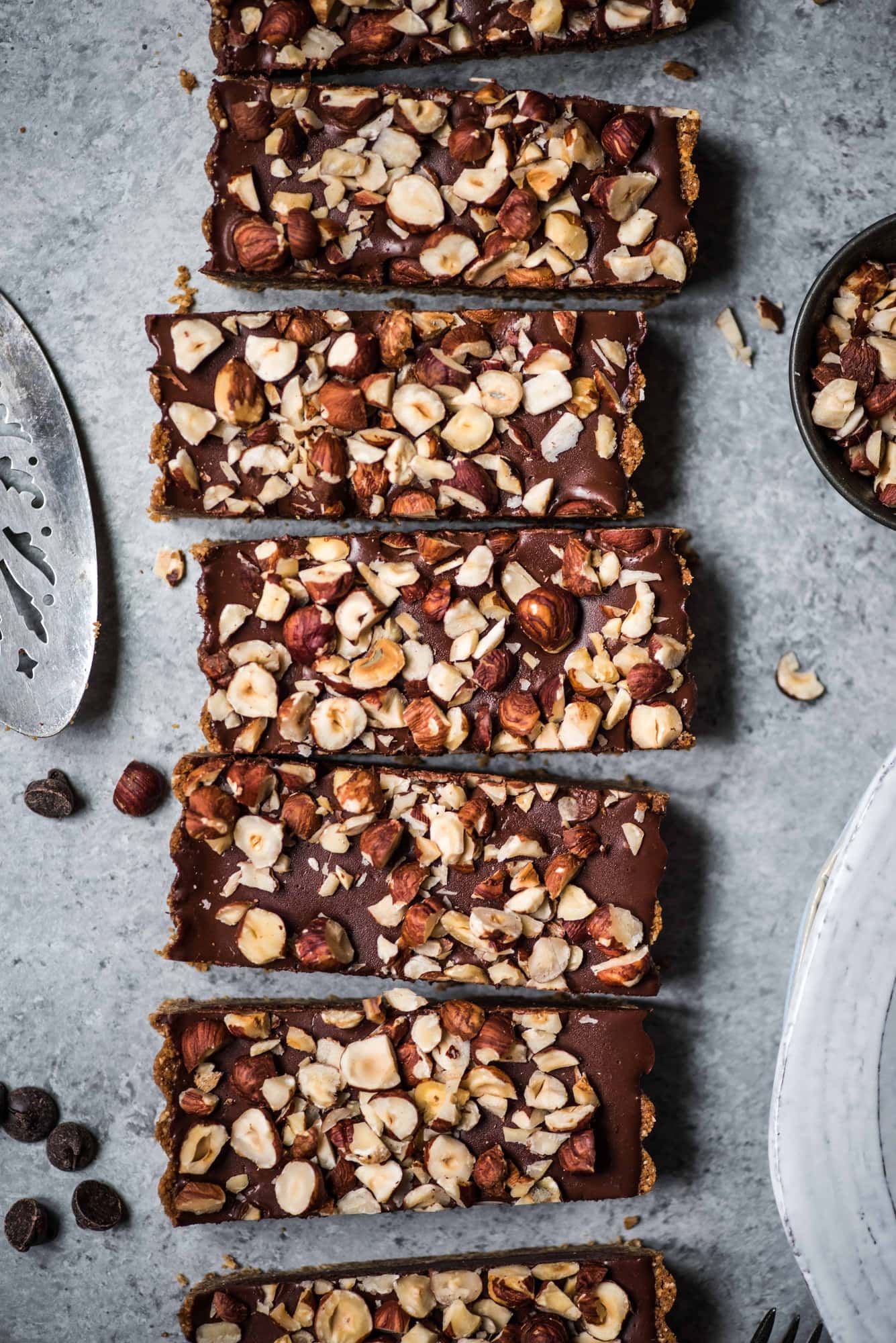 Overhead of vegan dark chocolate hazelnut ganache tart with crushed hazelnuts