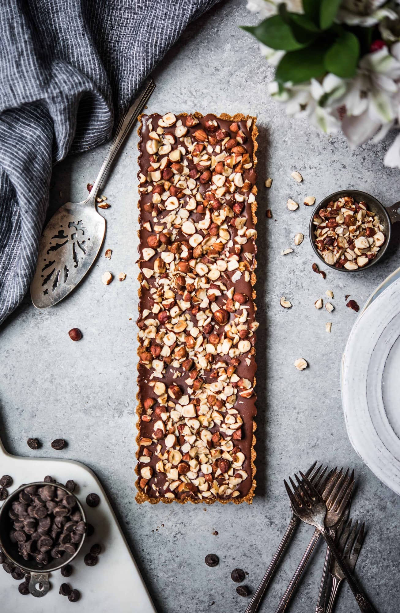 Overhead of rectangular chocolate hazelnut tart on light gray background