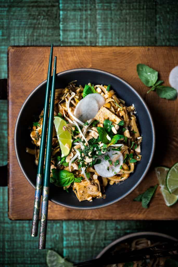 Overhead of vegan pad thai with chopsticks on rustic wood background