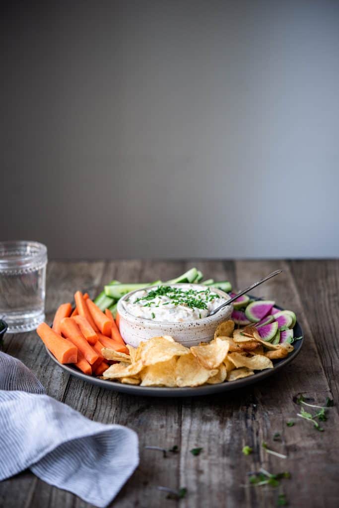 Side view of caramelized onion dip and vegetables on a wood table