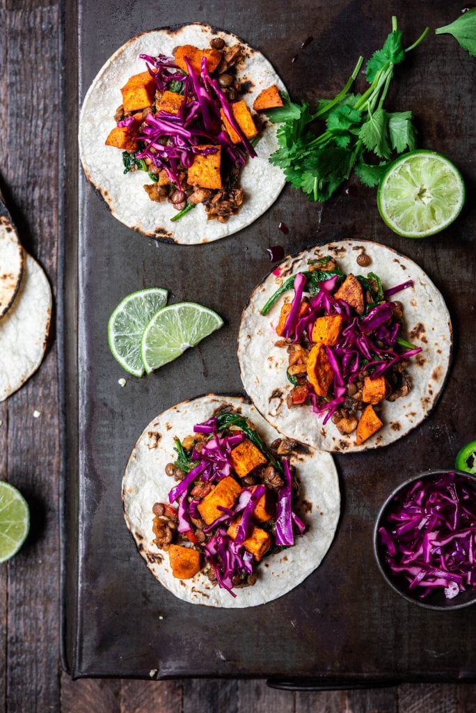 Overhead view of vegan lentil walnut tacos with roasted sweet potatoes, and cabbage on an antique serving tray