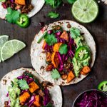 Overhead view of vegan lentil walnut tacos with roasted sweet potatoes, cabbage and guacamole on an antique serving tray