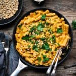 Overhead of roasted red pepper vegan pasta in a saute pan on a wood table