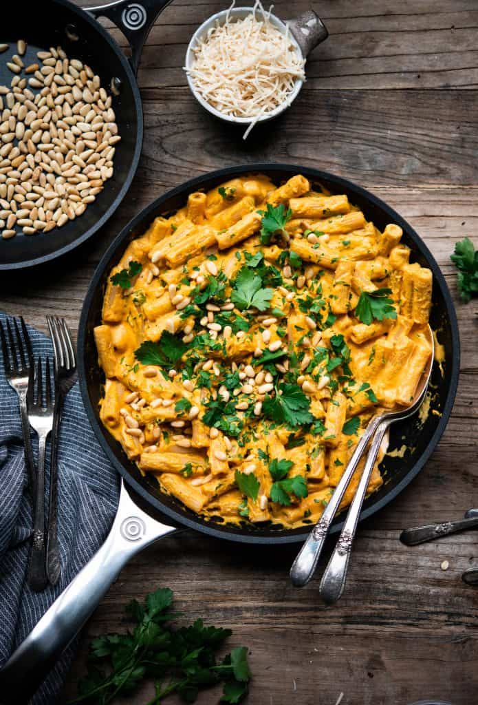 Overhead of roasted red pepper vegan pasta in a saute pan on a wood table
