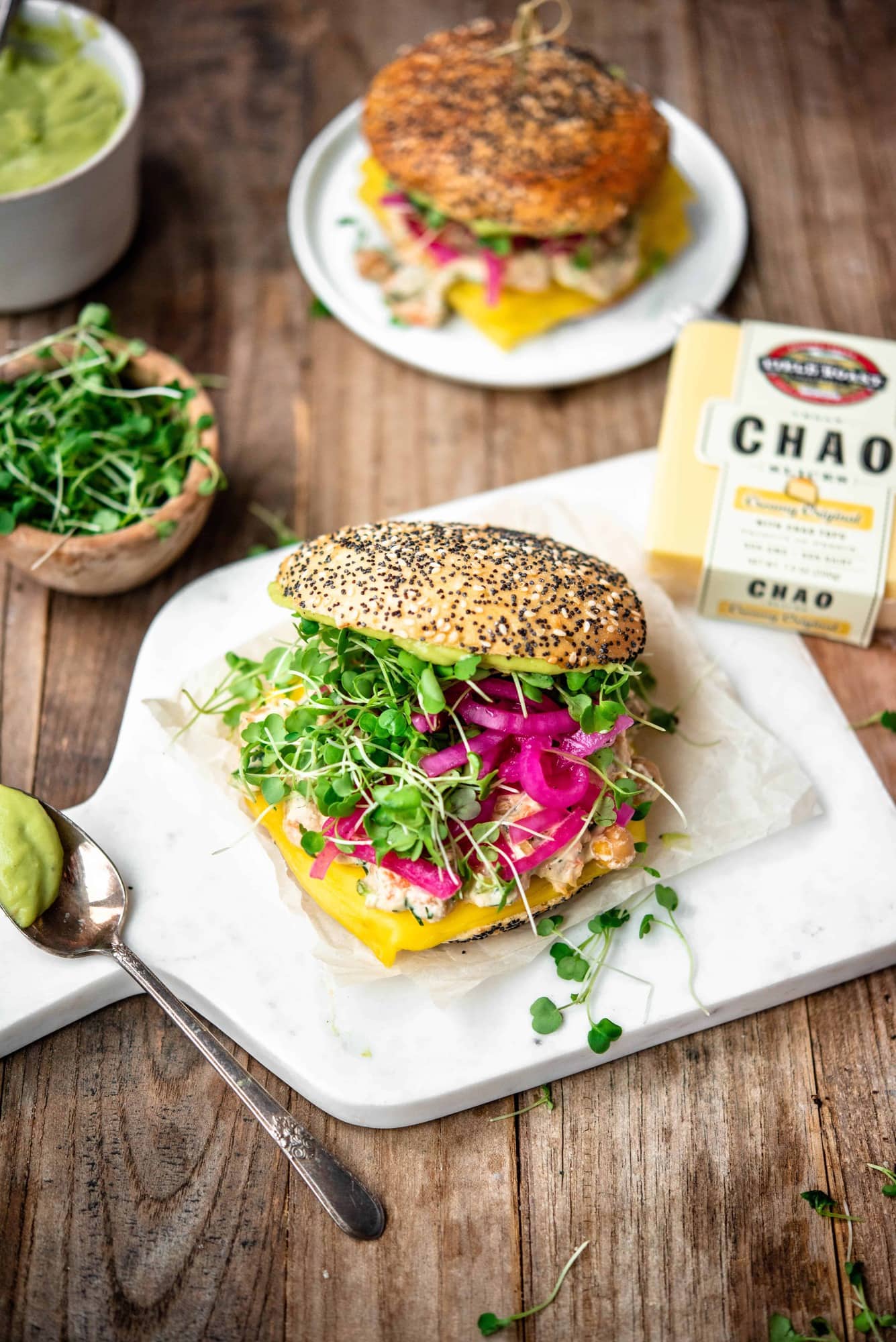 Side view of vegan chickpea melt with micro greens on a bun