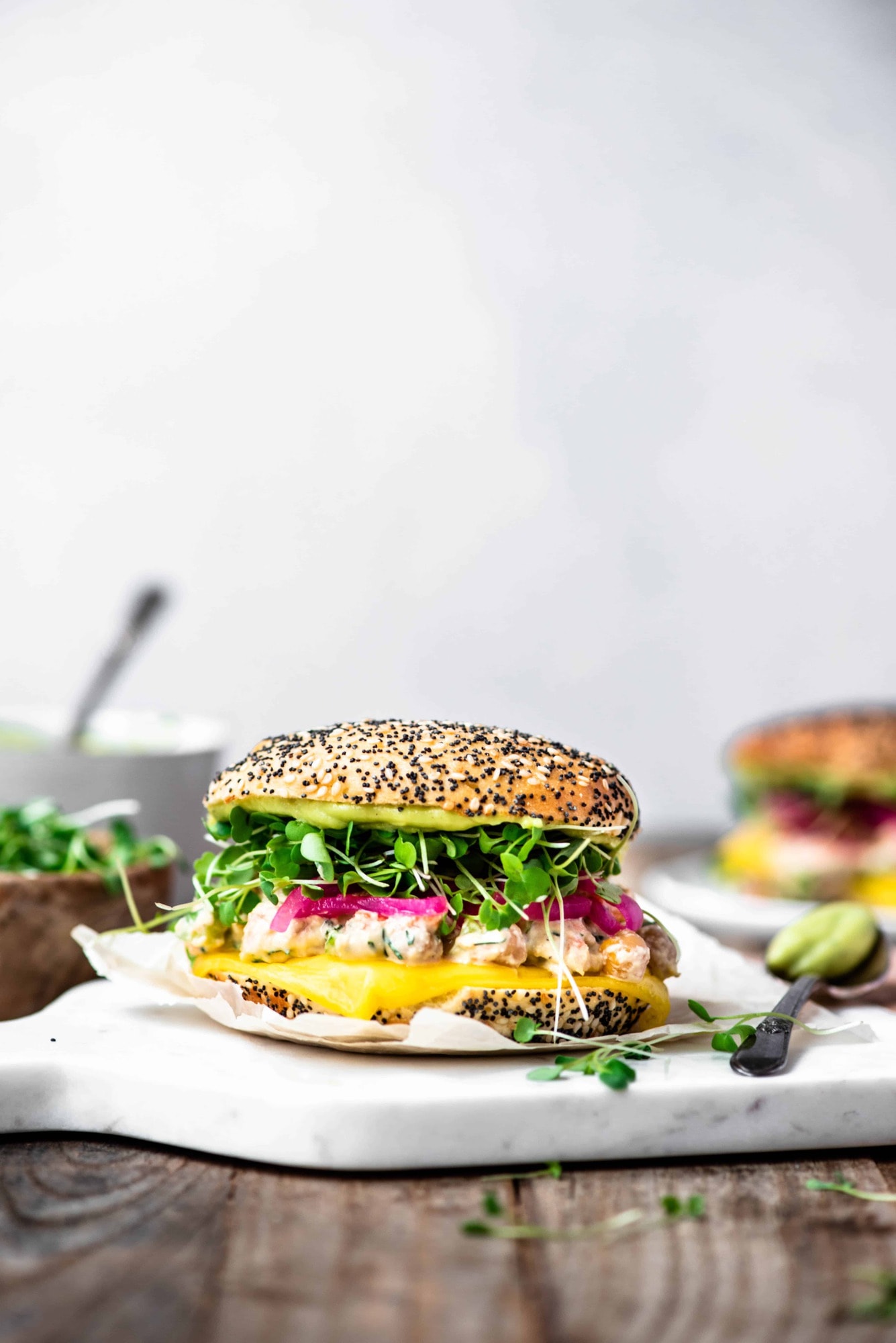 Side view of vegan chickpea melt with micro greens on a bun