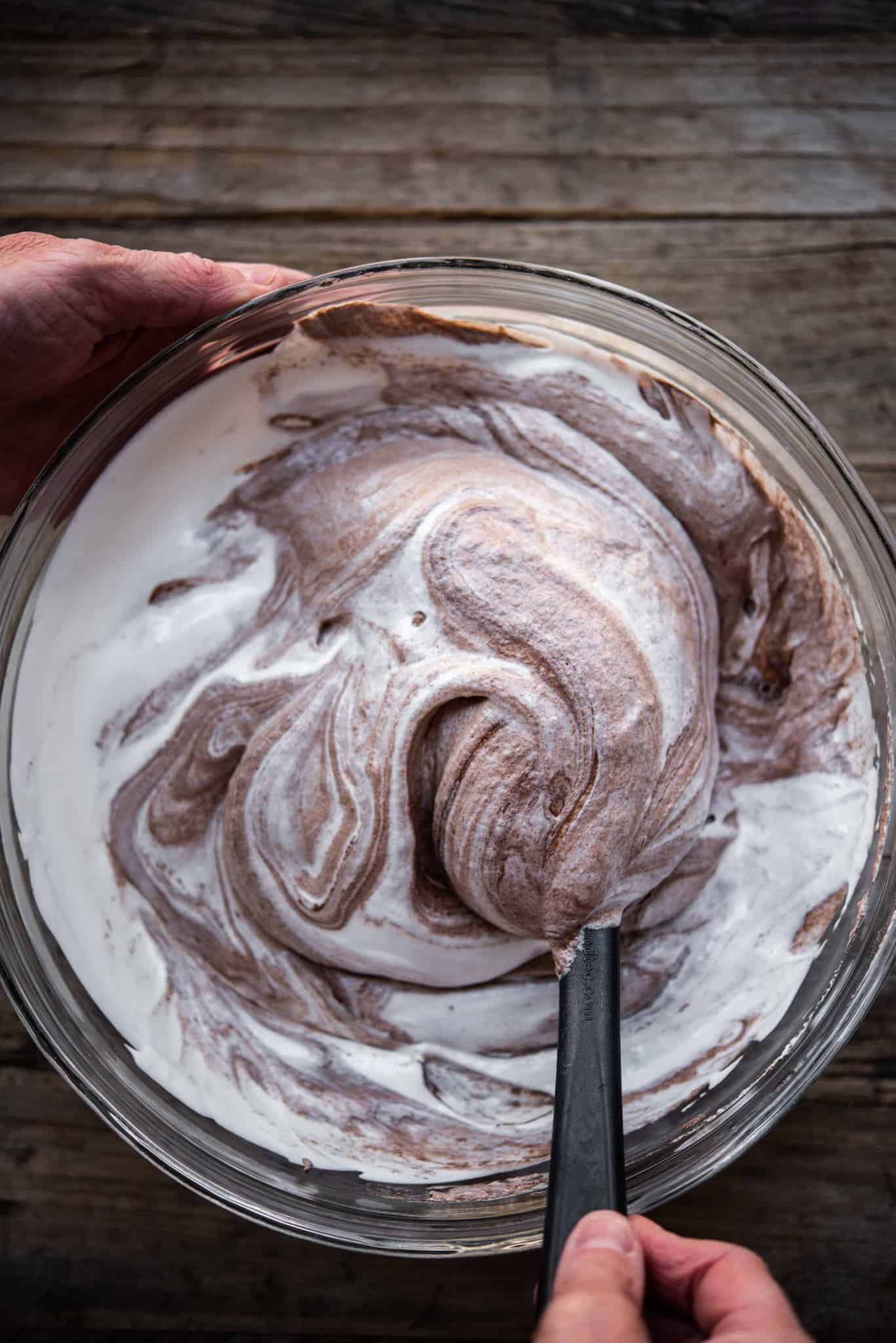 Person folding chocolate into whipped aquafaba to make mousse