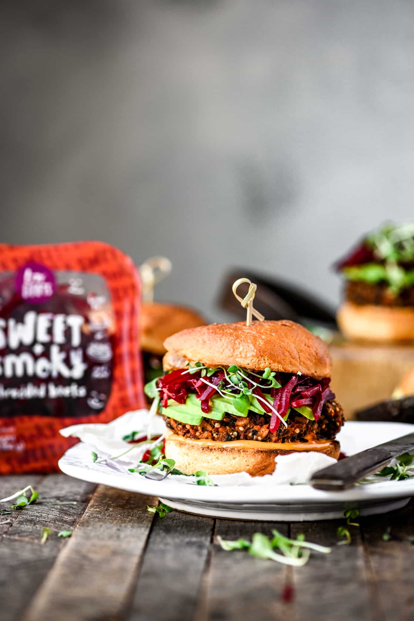 Side view of gluten free veggie burger with smoky shredded beets an avocado