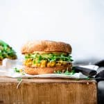 Side view of scrambled tofu and avocado breakfast sandwich on an english muffin