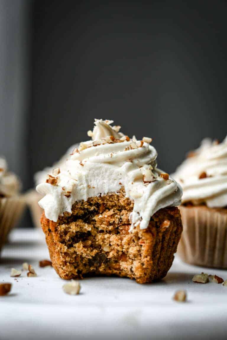 Side view of carrot cake cupcake with cream cheese frosting with bite taken out