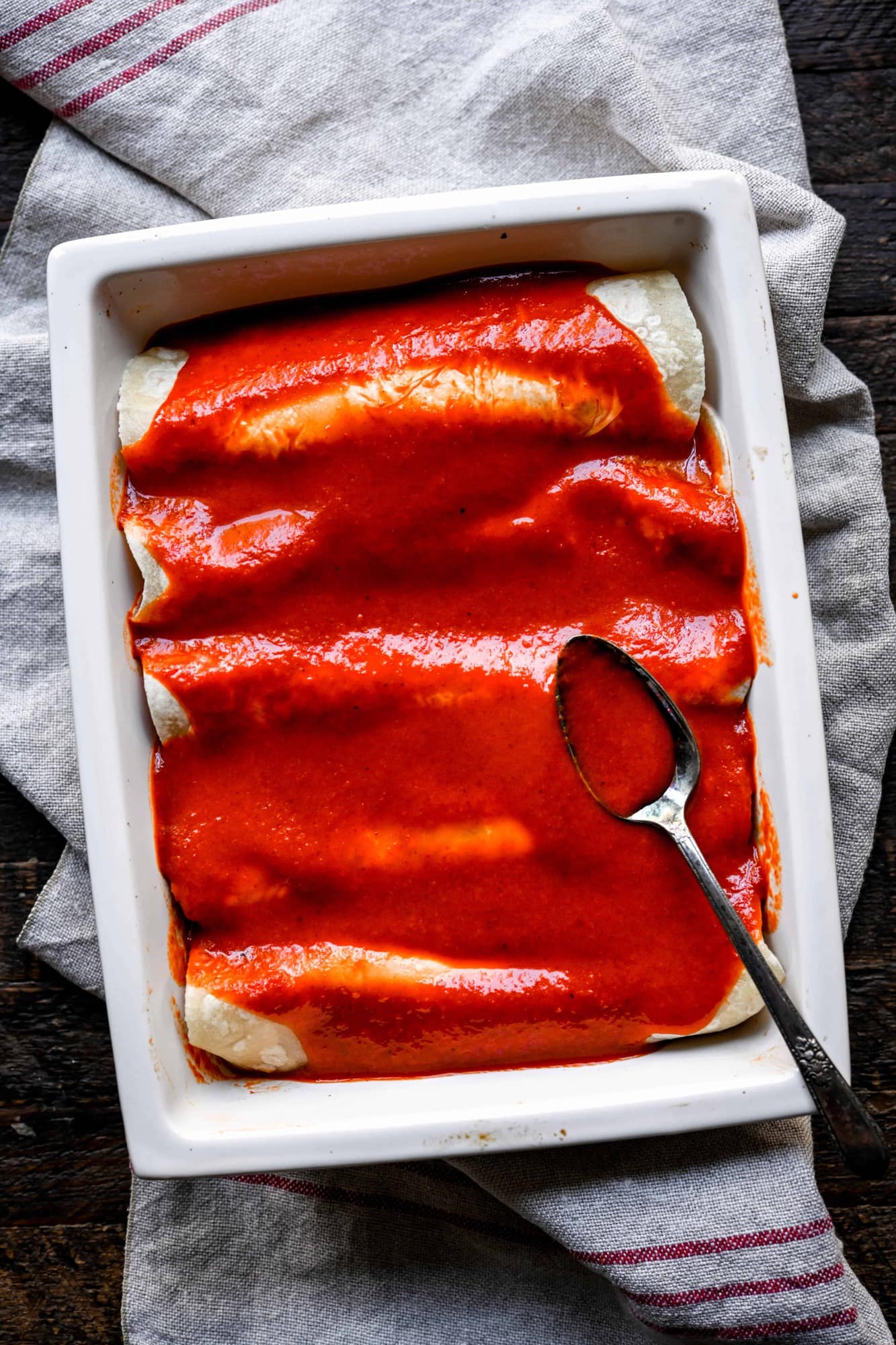 Overhead view of vegan enchiladas in a white pan before going in the oven with Mexican enchilada sauce