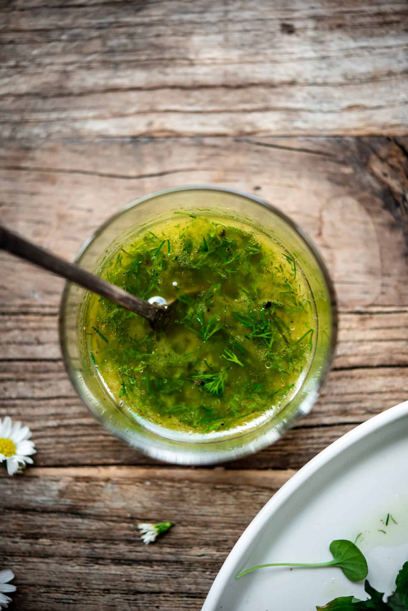 Close up view of dill vinaigrette in a small glass jar on wood table