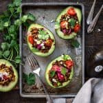 Overhead view of vegan taco stuffed avocados on a sheet pan on wood background
