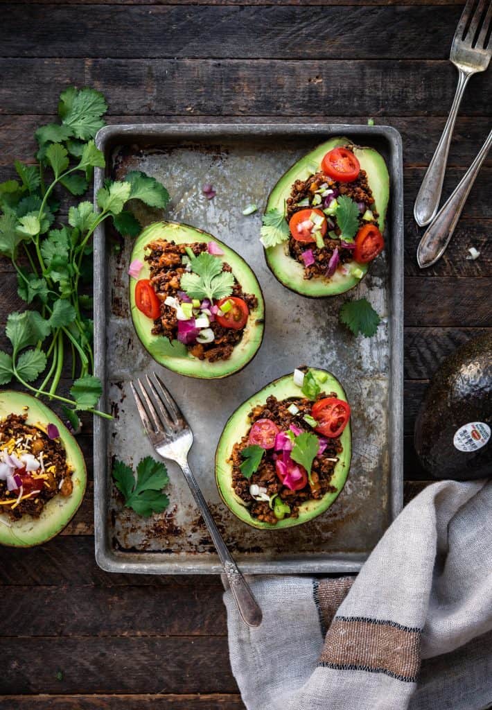 Overhead view of vegan taco stuffed avocados on a sheet pan on wood background