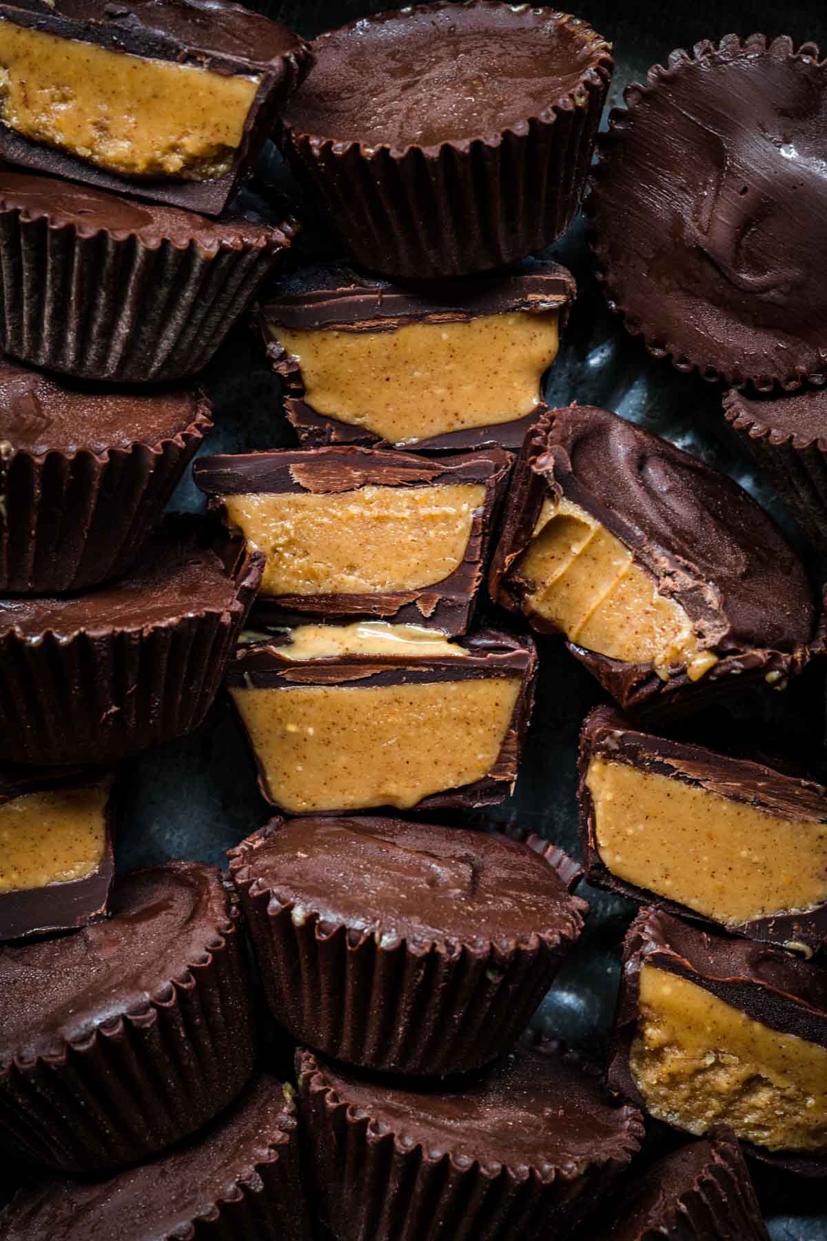close up overhead view of vegan peanut butter cups on tin tray with some sliced in half and some whole. 