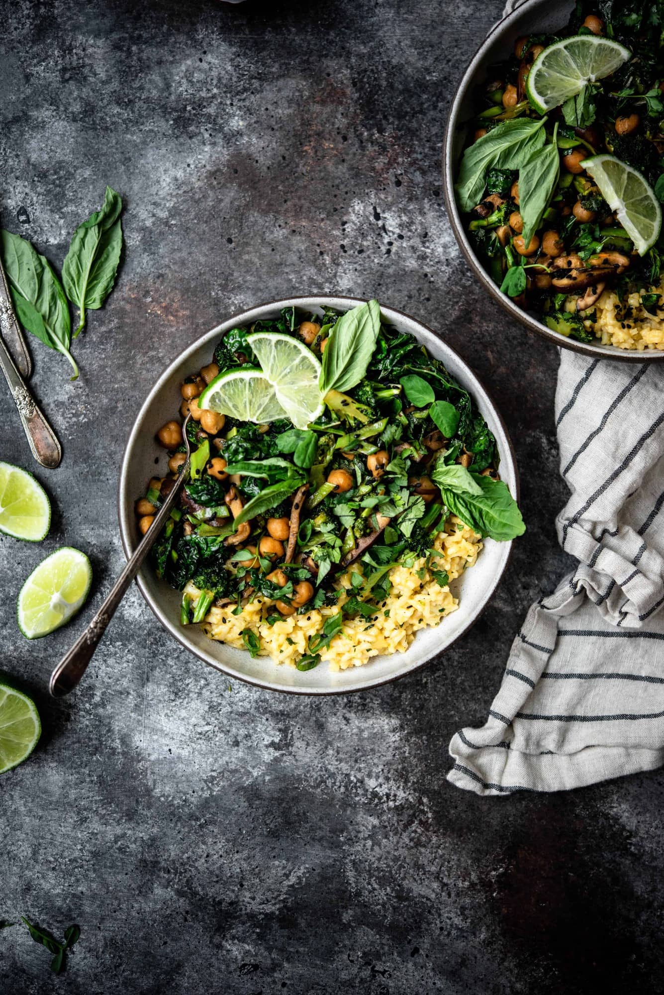 Overhead view of green curry coconut rice with stir fried vegetables, mushrooms, chickpeas and herbs with a striped linen