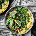 Overhead view of green curry coconut rice with stir fried vegetables, mushrooms, chickpeas and herbs on a striped linen