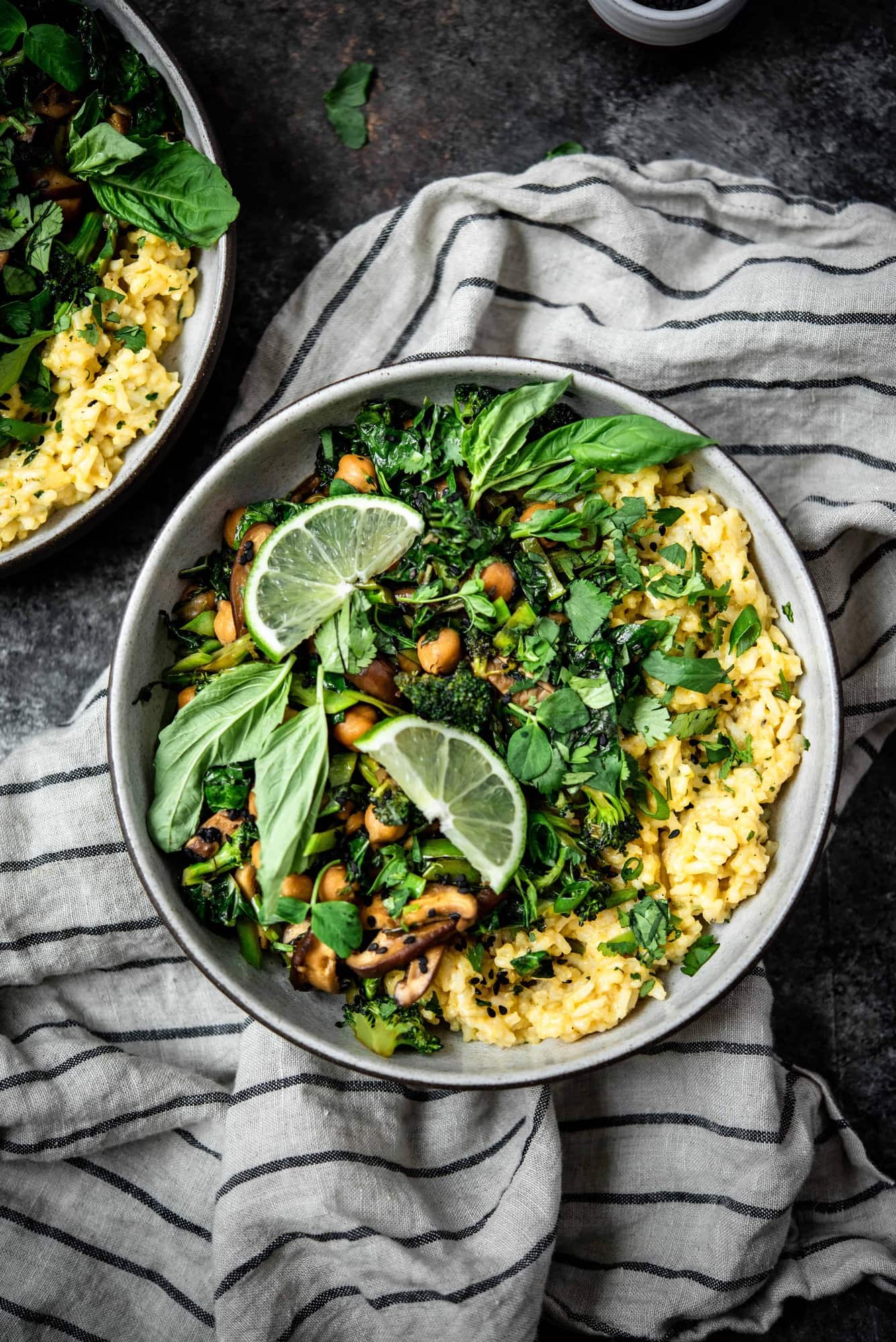 Overhead view of green curry coconut rice with stir fried vegetables, mushrooms, chickpeas and herbs on a striped linen