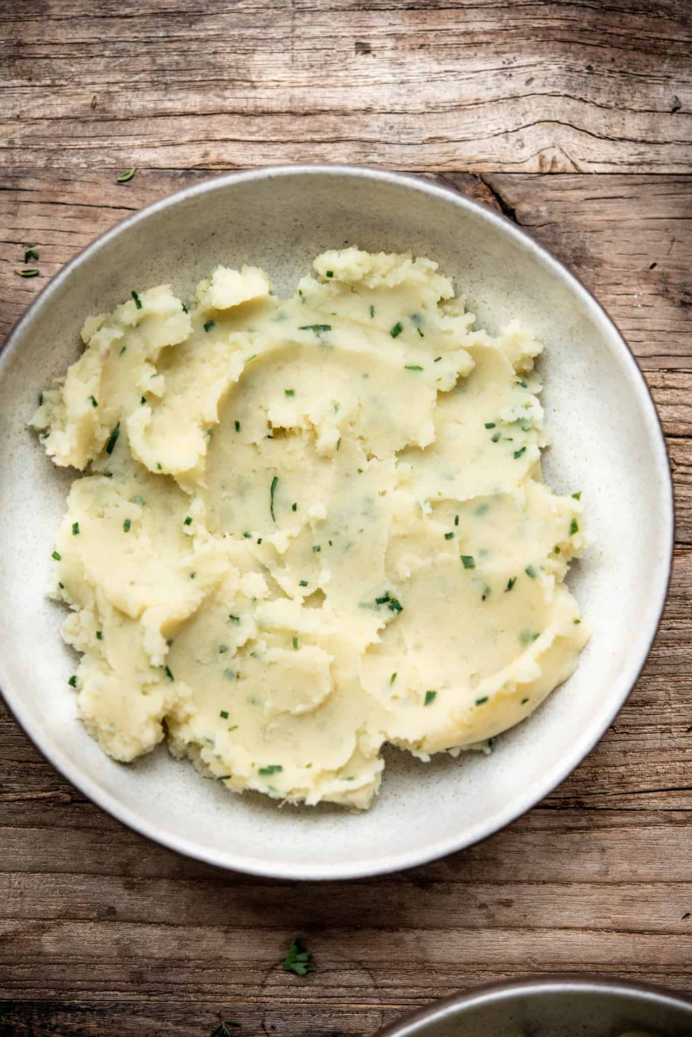 Overhead view of roasted garlic chive mashed potatoes in a white bowl