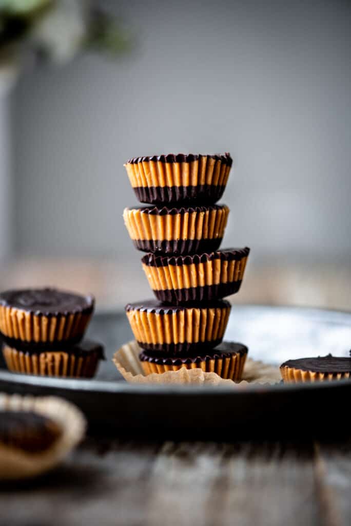 Stack of vegan peanut butter cups on an antique tray with white background