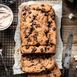 Overhead view of banana bread on a cooling rack and parchment paper
