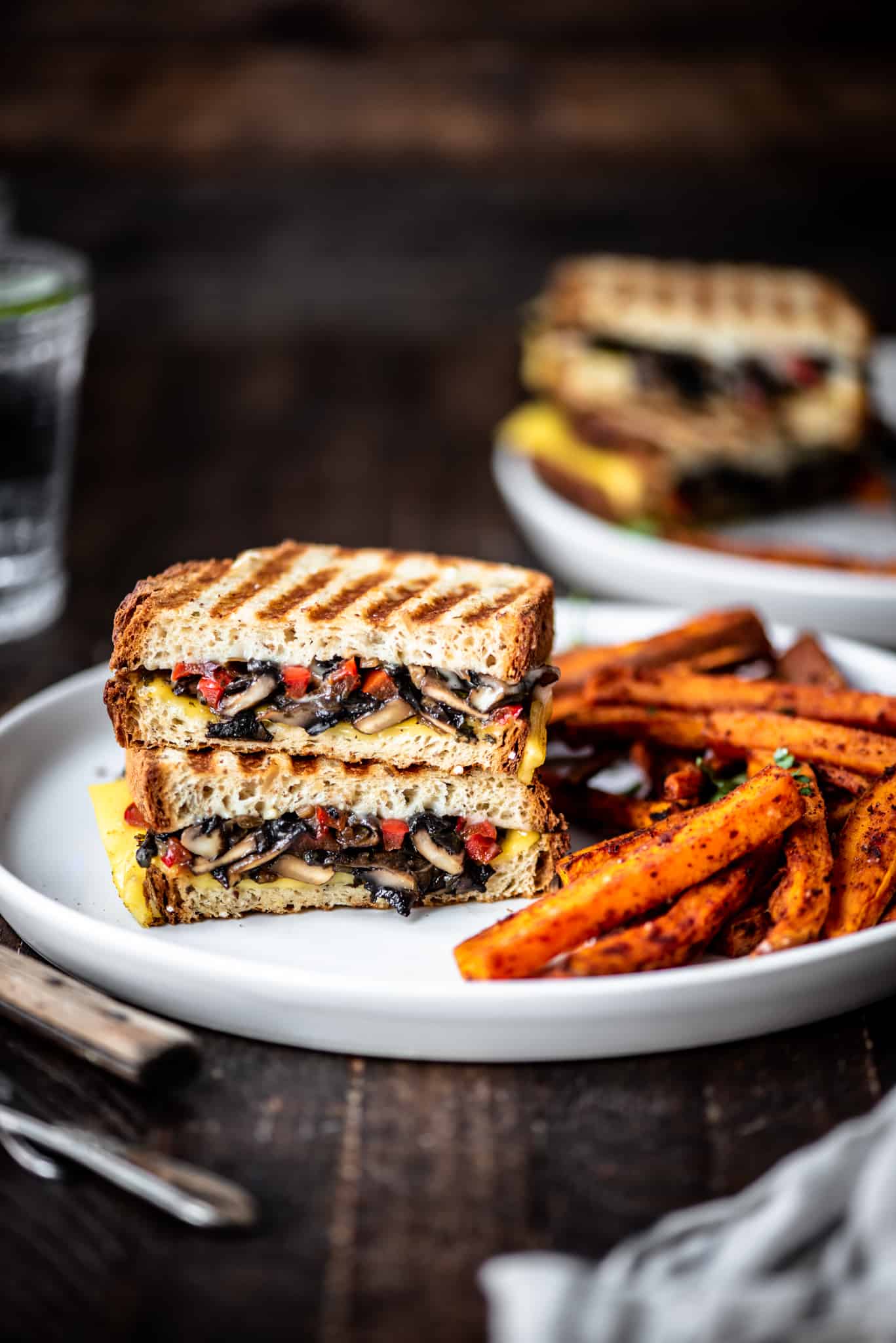 Side view of gluten free mushroom panini on a white plate with sweet potato fries