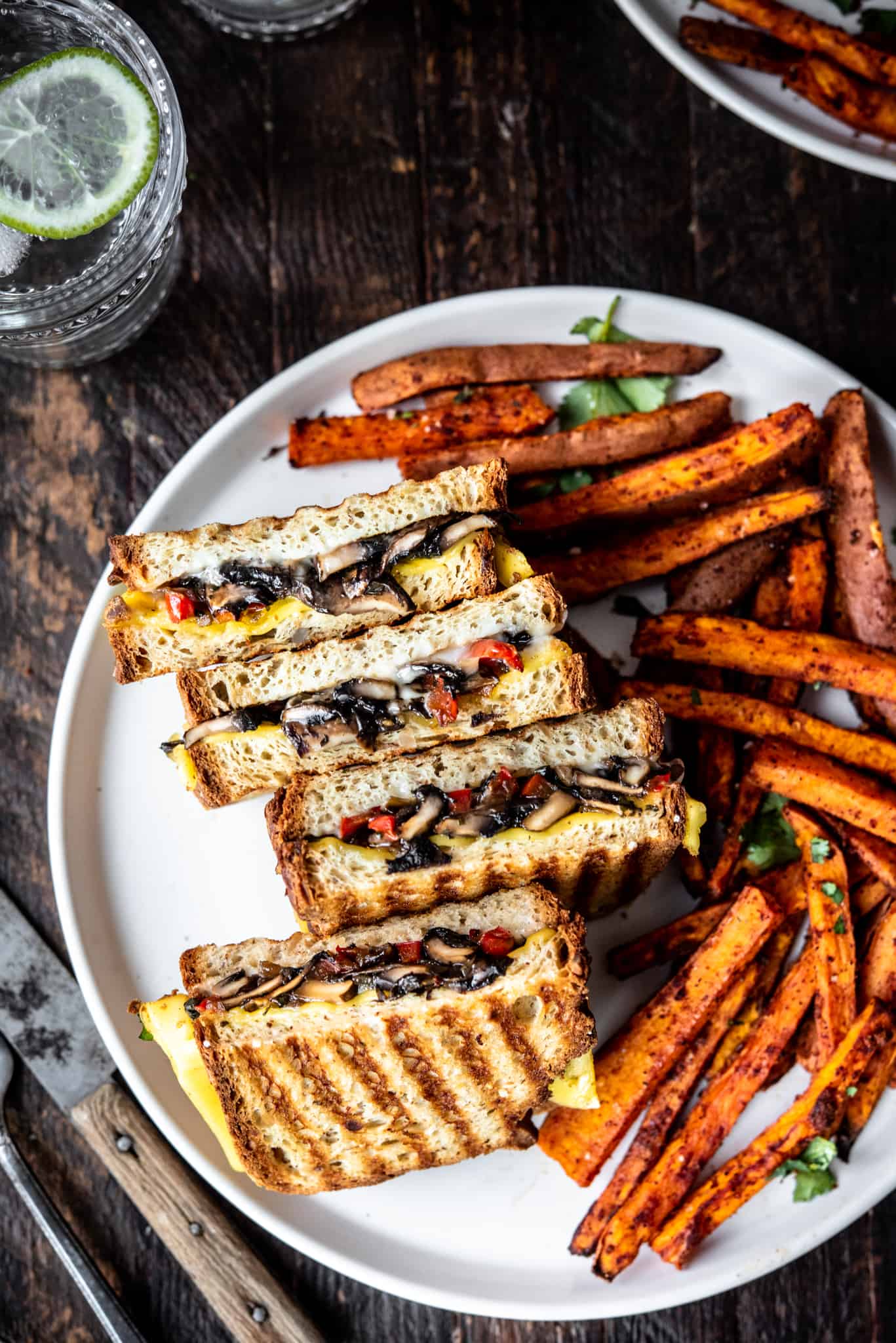 Overhead of gluten free mushroom panini on a white plate with sweet potato fries