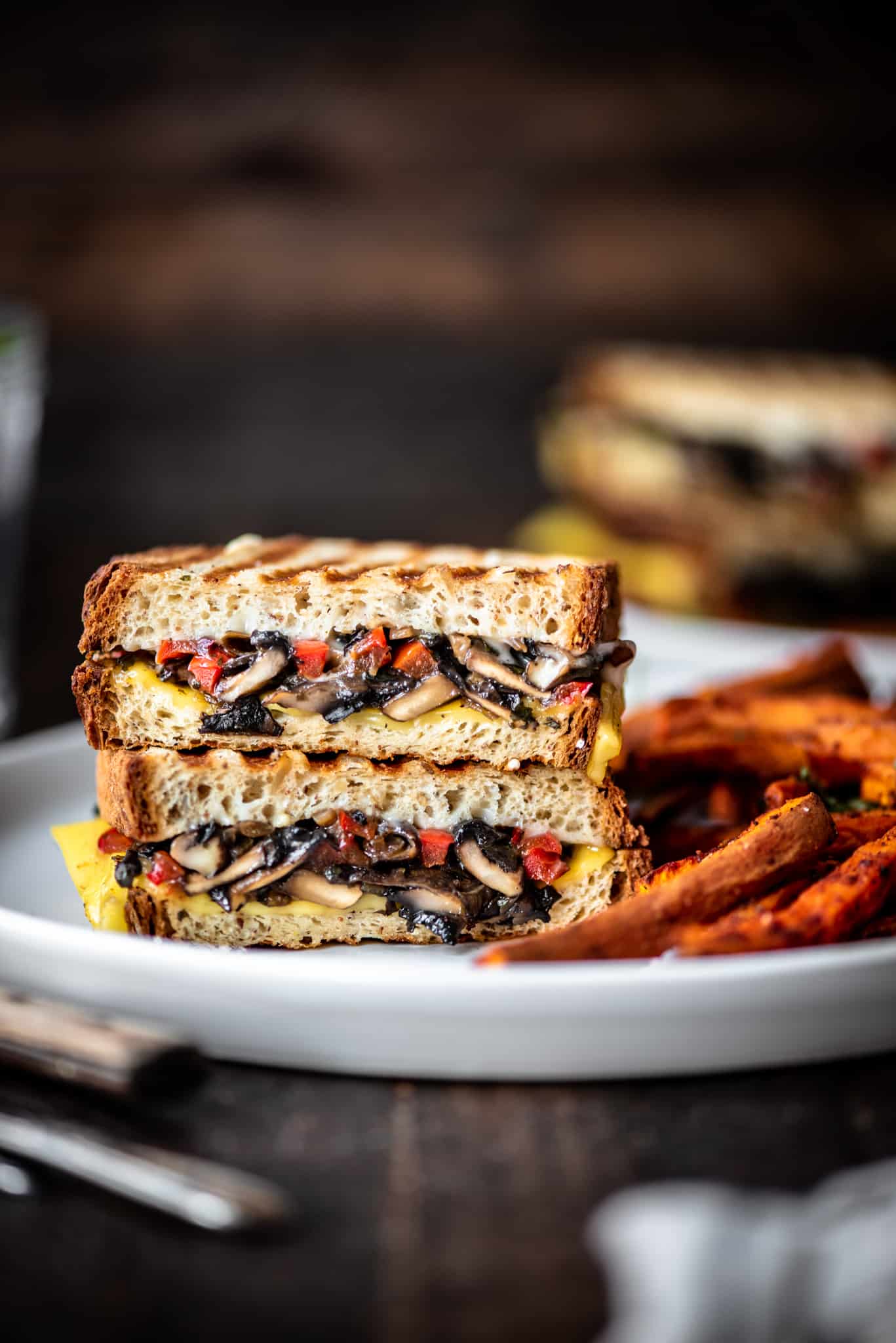 Side view of gluten free mushroom panini on a white plate with sweet potato fries
