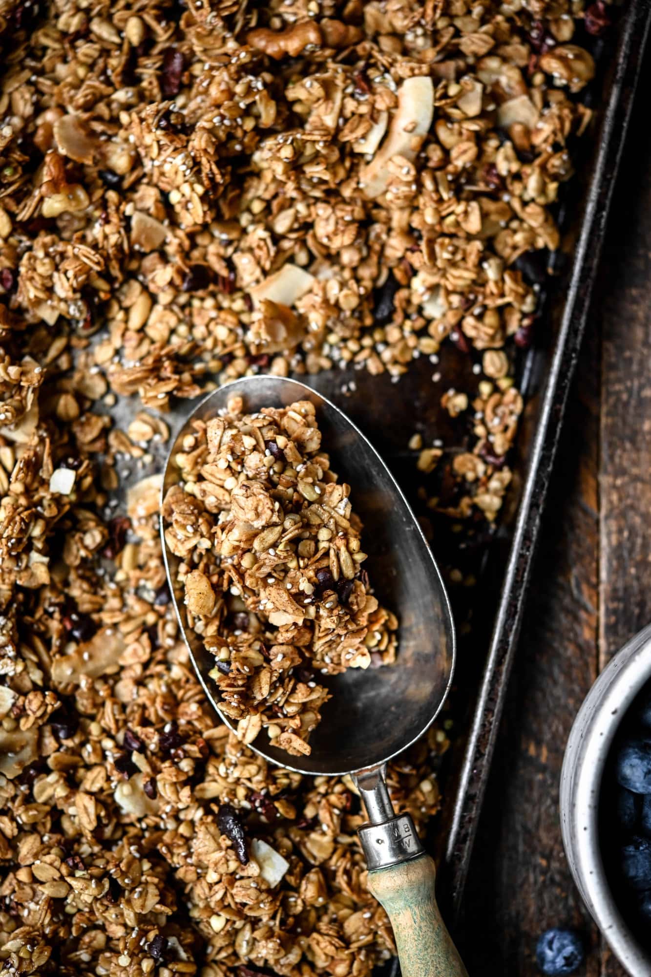 Overhead view of gluten free granola on a sheet pan, close up view of granola in a scoop