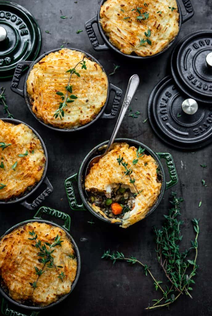 Overhead of vegan lentil shepherd's pie with mashed potatoes in mini Staub cocottes