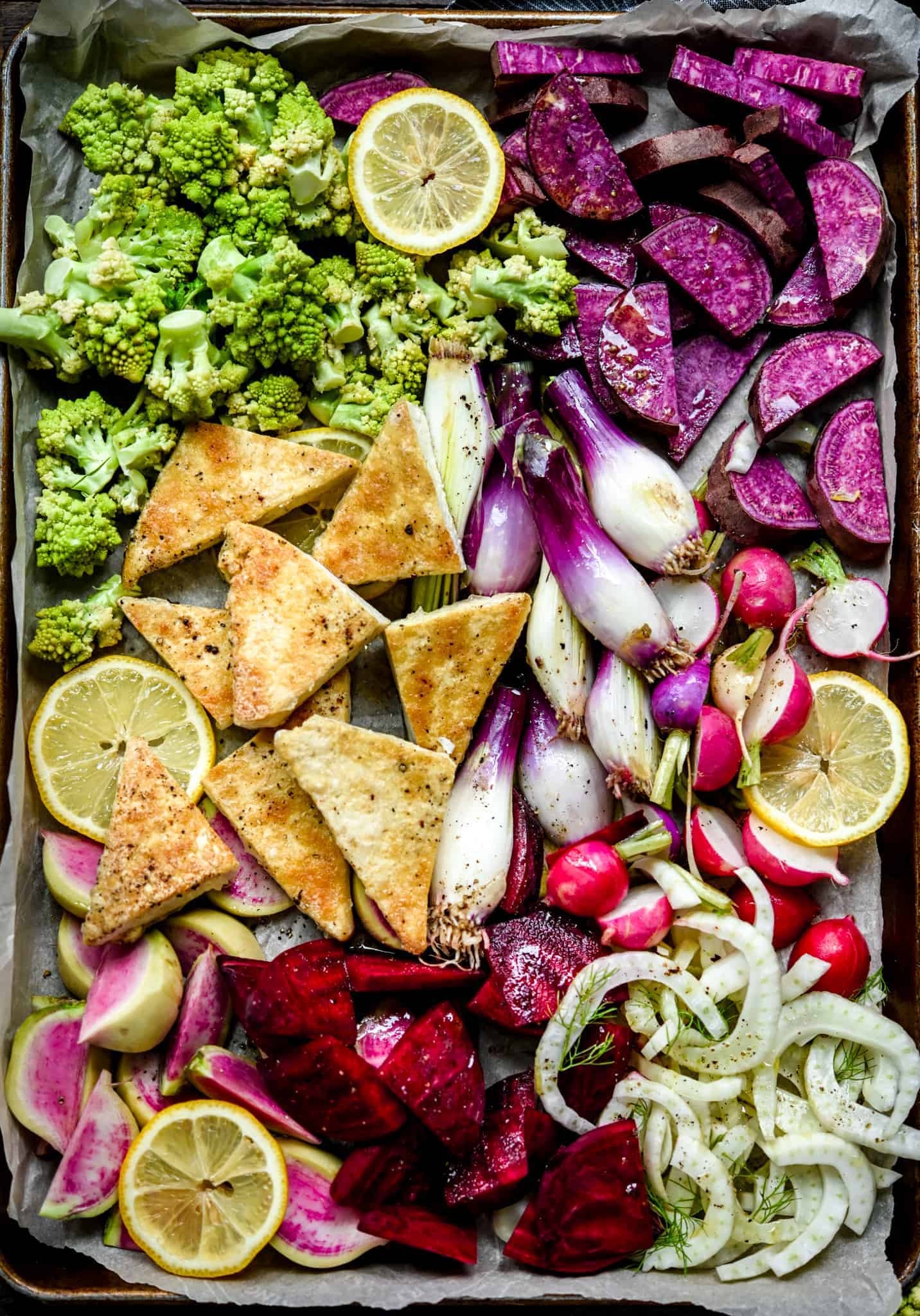 Overhead of sheet pan with uncooked purple, pink and green vegetables and tofu