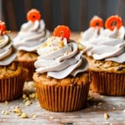 Front view of carrot cake cupcakes with a carrot garnish.