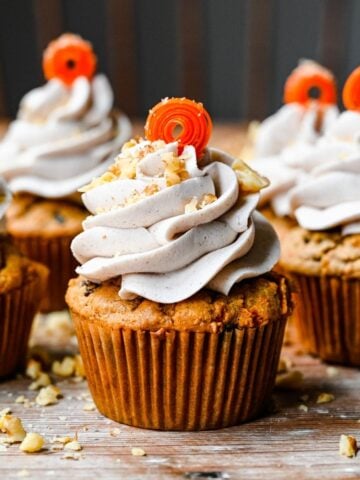 Front view of carrot cake cupcakes with a carrot garnish.
