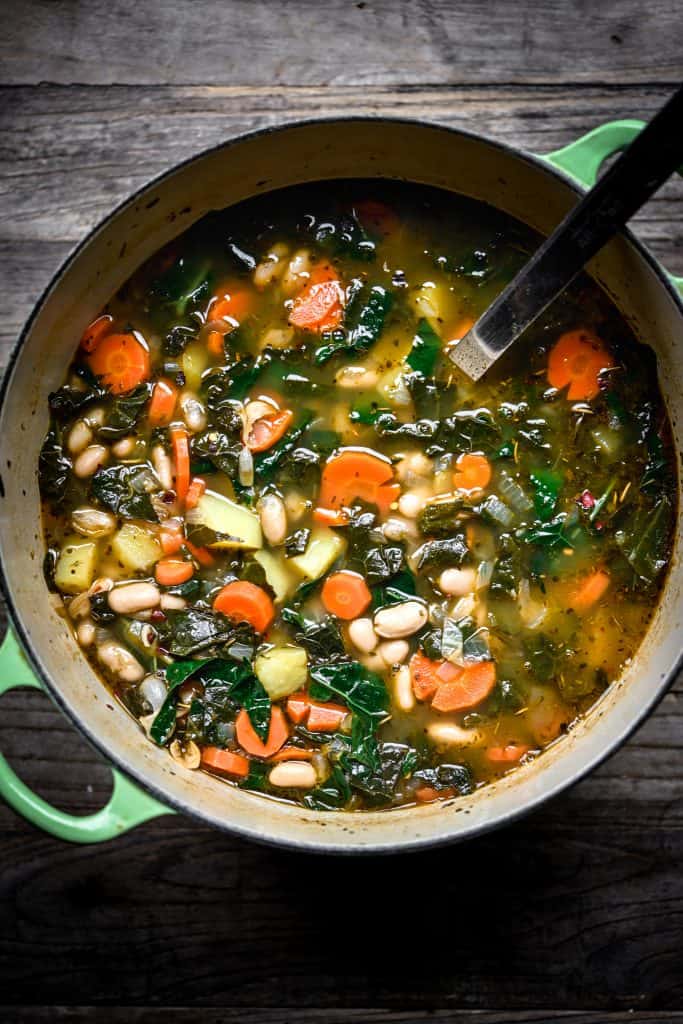 Overhead view of one-pot white bean kale soup in a green stock pot