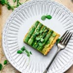 Overhead view of slice of vegan ricotta and asparagus tart on a white plate with fork