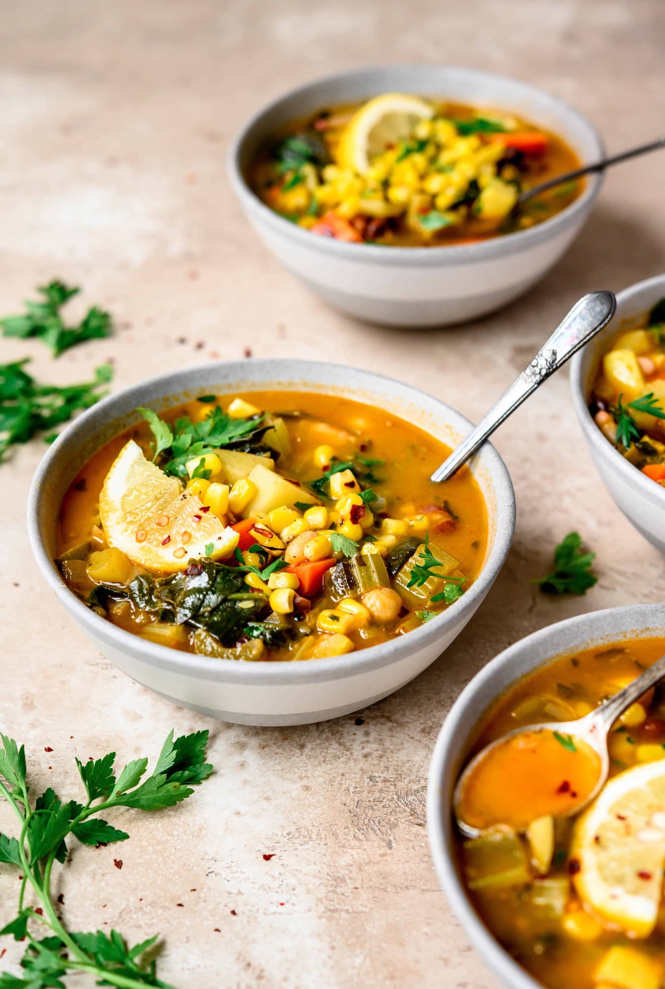 Side view of white bean vegetable soup in a light grey bowl on light brown background