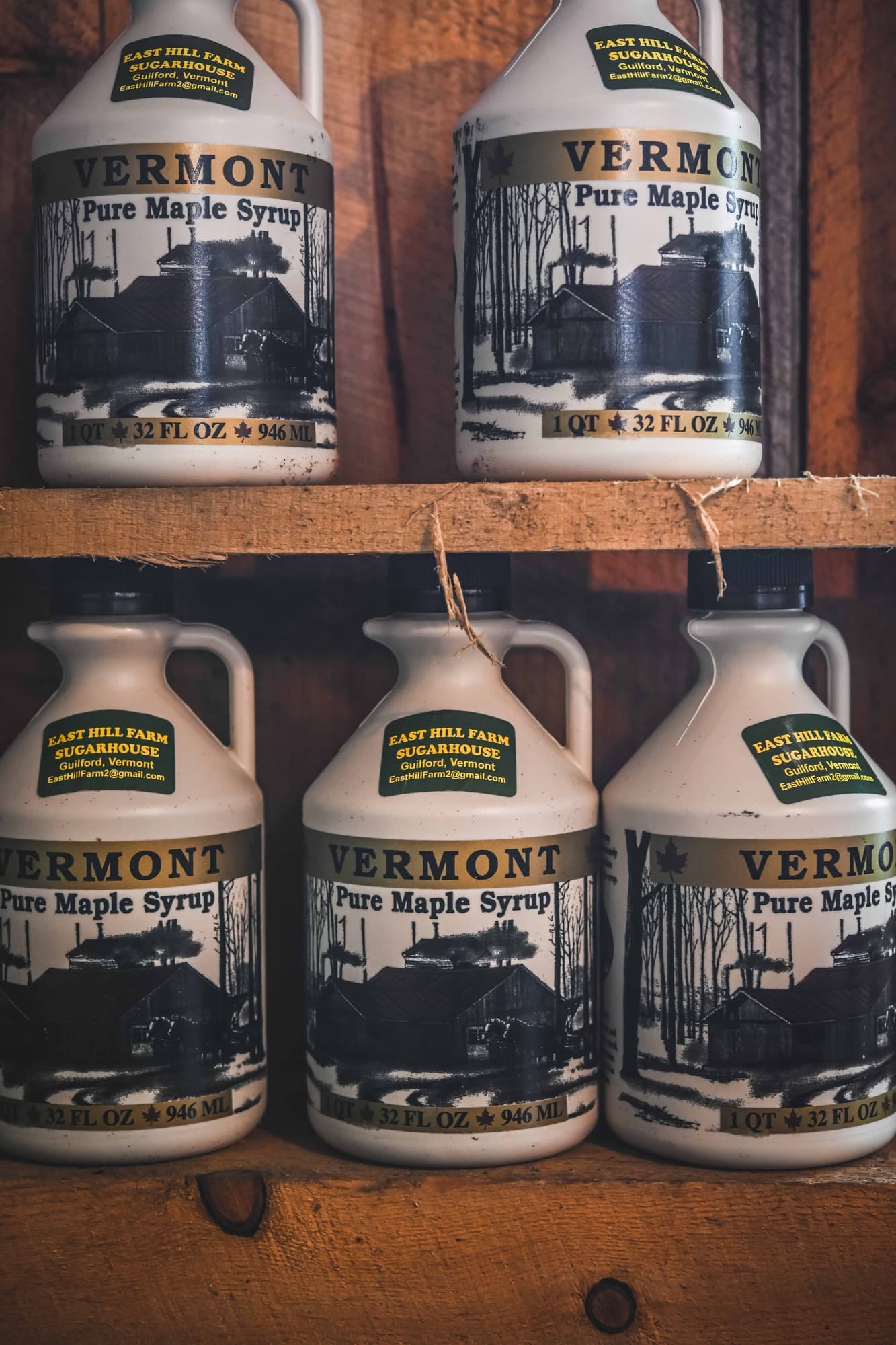 Close up of large jugs of Vermont maple syrup on wood shelves