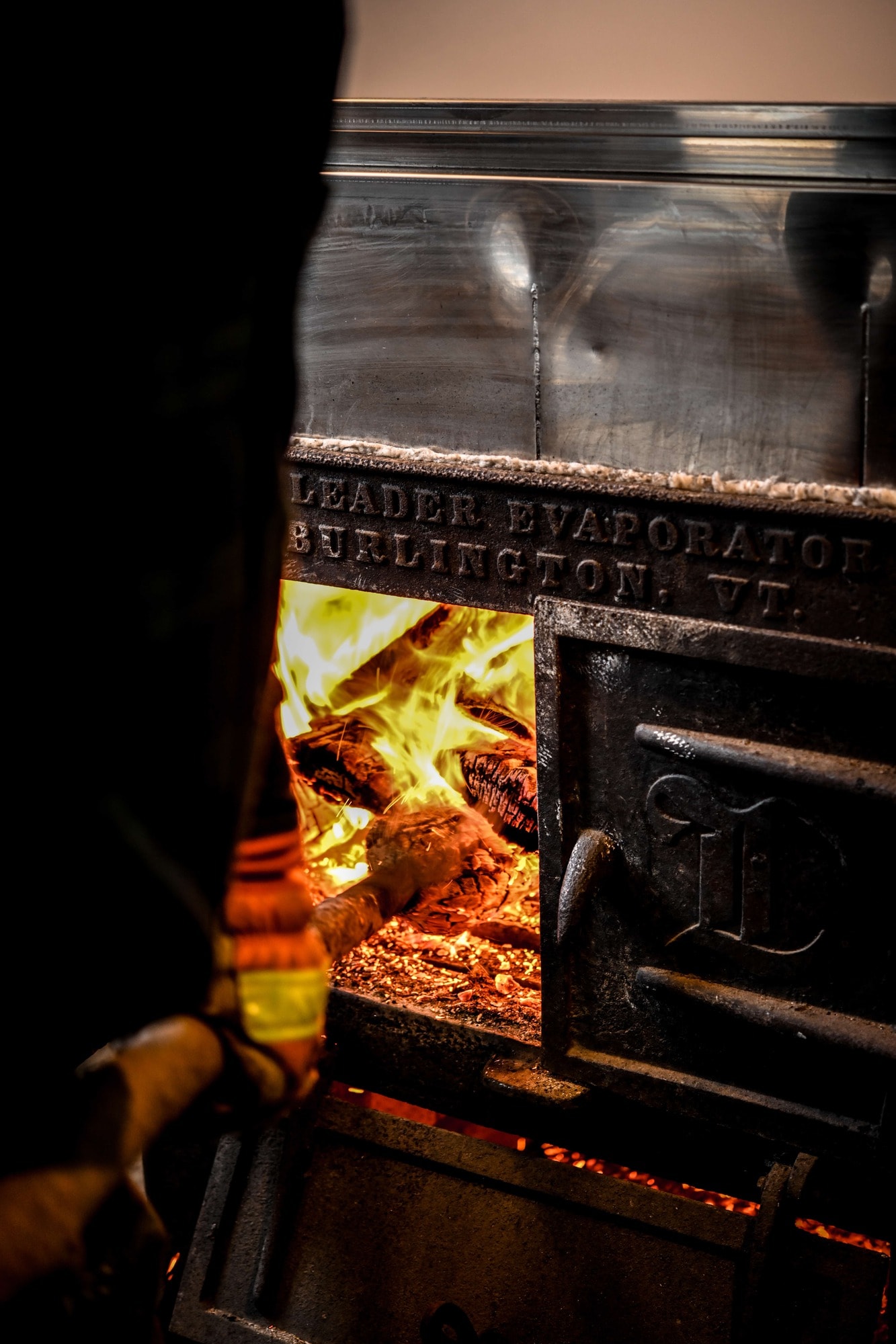 Person adding wood to a large wood burning stove